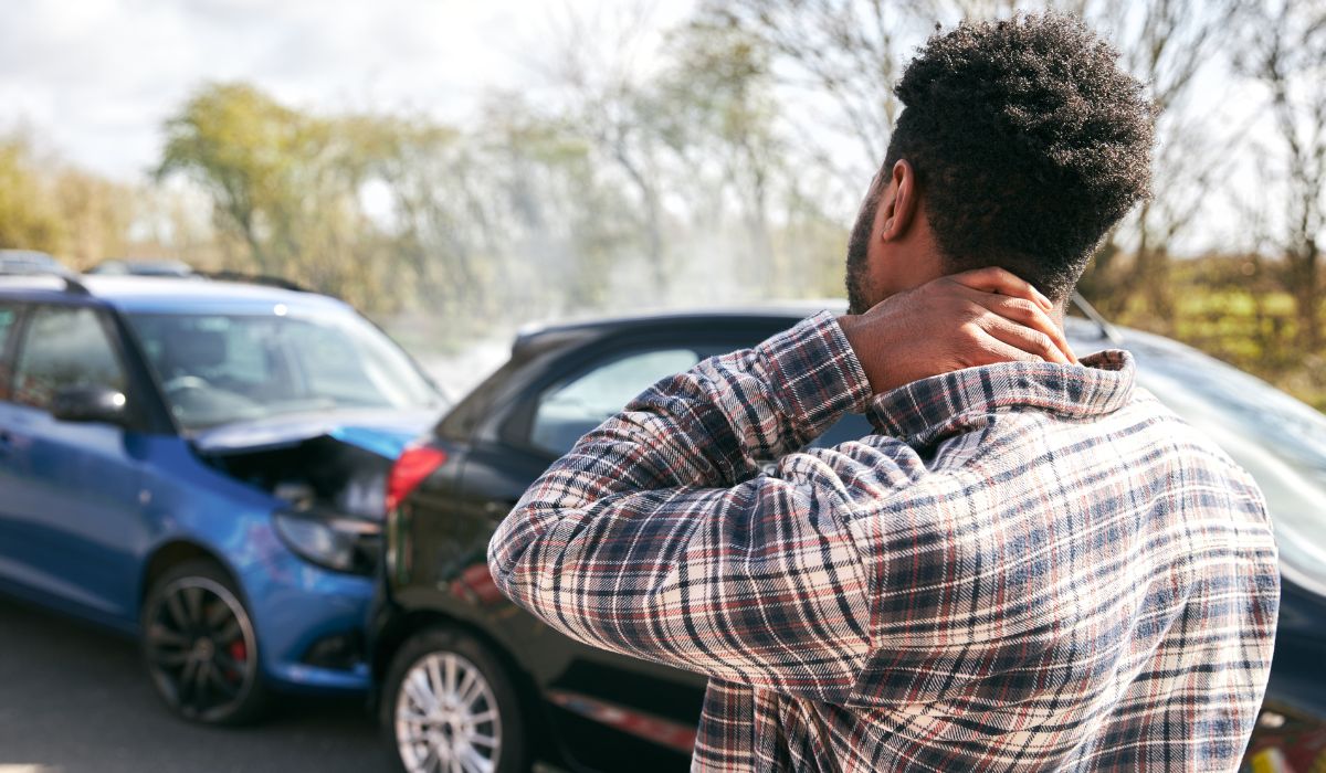 Person holding their neck in discomfort beside their car after a car accident in Schuylkill County, PA