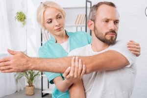 physiotherapist stretching mans arm